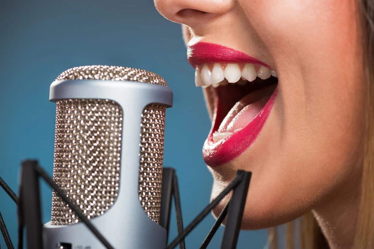 A close-up image of a woman's mouth speaking into a microphone.