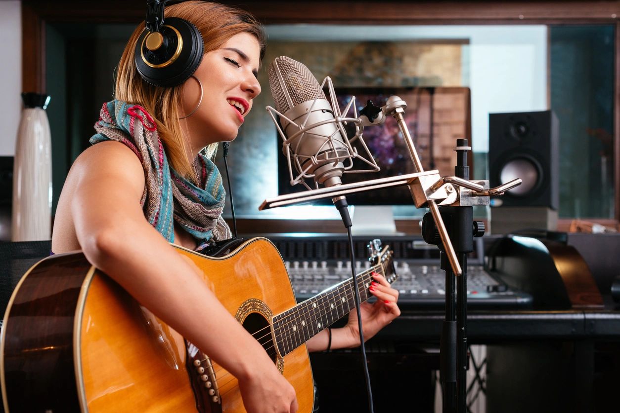 A woman playing the guitar in a sound design studio.