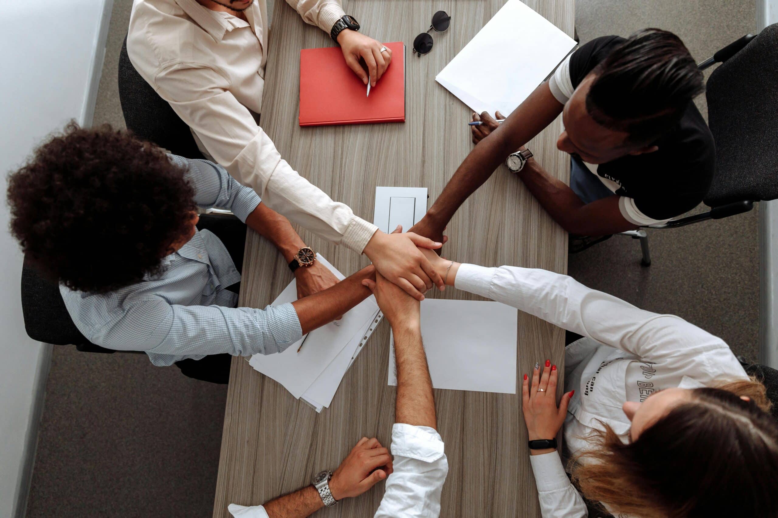 A group of people at a conference table putting their hands together. This is definitely related to corporate social responsibility (CSR)!