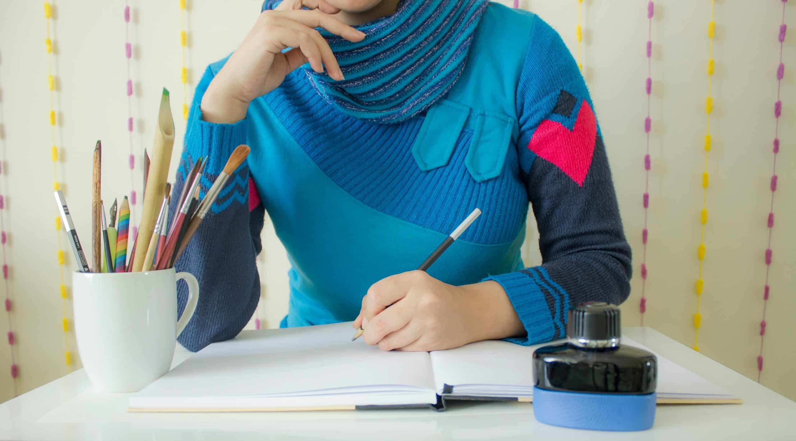 Woman in a colorful sweater drawing on a white desk